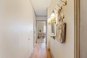 A hallway with a wooden floor, a dining area in the background, and wall-mounted lighting fixtures. - Twee Seen 33 - "Twee Seen 33" Vacation Rental (Kampen (Sylt))