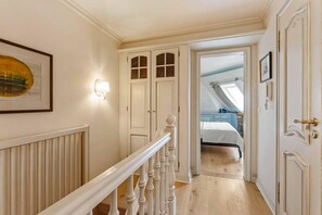 A hallway with a white railing, a framed picture on the wall, and a door leading to a bedroom with a skylight. - Twee Seen 33 - "Twee Seen 33" Vacation Rental (Kampen (Sylt))