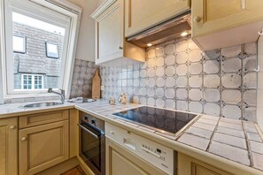 A kitchen with a built-in stove, a window, and a tiled backsplash. - Twee Seen 33 - "Twee Seen 33" Vacation Rental (Kampen (Sylt))