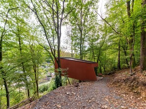 A pathway in a forested area with a red structure on the right. - The Serene Escape - Olivenise Cabin (La Roche-en-Ardenne)