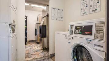 A laundry area with a washing machine, dryer, and control panel. There are signs with laundry tips and service information.