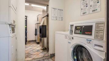 Une buanderie équipée d’un lave-linge à chargement frontal, d’un sèche-linge et d’un panneau de commande fixé au mur.