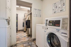 Una lavanderia con lavatrice a carica frontale, asciugatrice e pannello di controllo a parete.