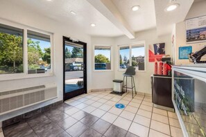 A clean, well-lit indoor space with a tiled floor, a bench, a trash bin, and a counter with a poster.