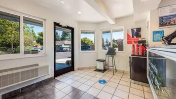 A clean, well-lit indoor space with a tiled floor, a bench, a trash bin, and a counter with a poster.