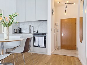 A modern kitchen with white cabinets, a stainless steel sink, and a wooden door. - Franz Josef by Interhome (Bad Gastein)