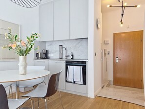 A modern kitchen with white cabinets, a coffee machine, and a hanging light fixture. - Franz Josef by Interhome (Bad Gastein)