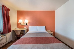 Habitació d'hotel amb un llit, dues làmpades de nit, un escriptori amb una cadira i una finestra amb cortines.