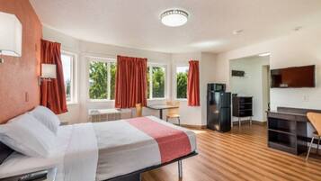 Een hotelkamer met een bed, een bureau, een koelkast en een televisie.