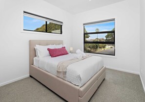 A bedroom with a bed, two windows, and a view of the outside. - Reid Street Retreat,  Stylish 4B Coastal Stay (Shellharbour)