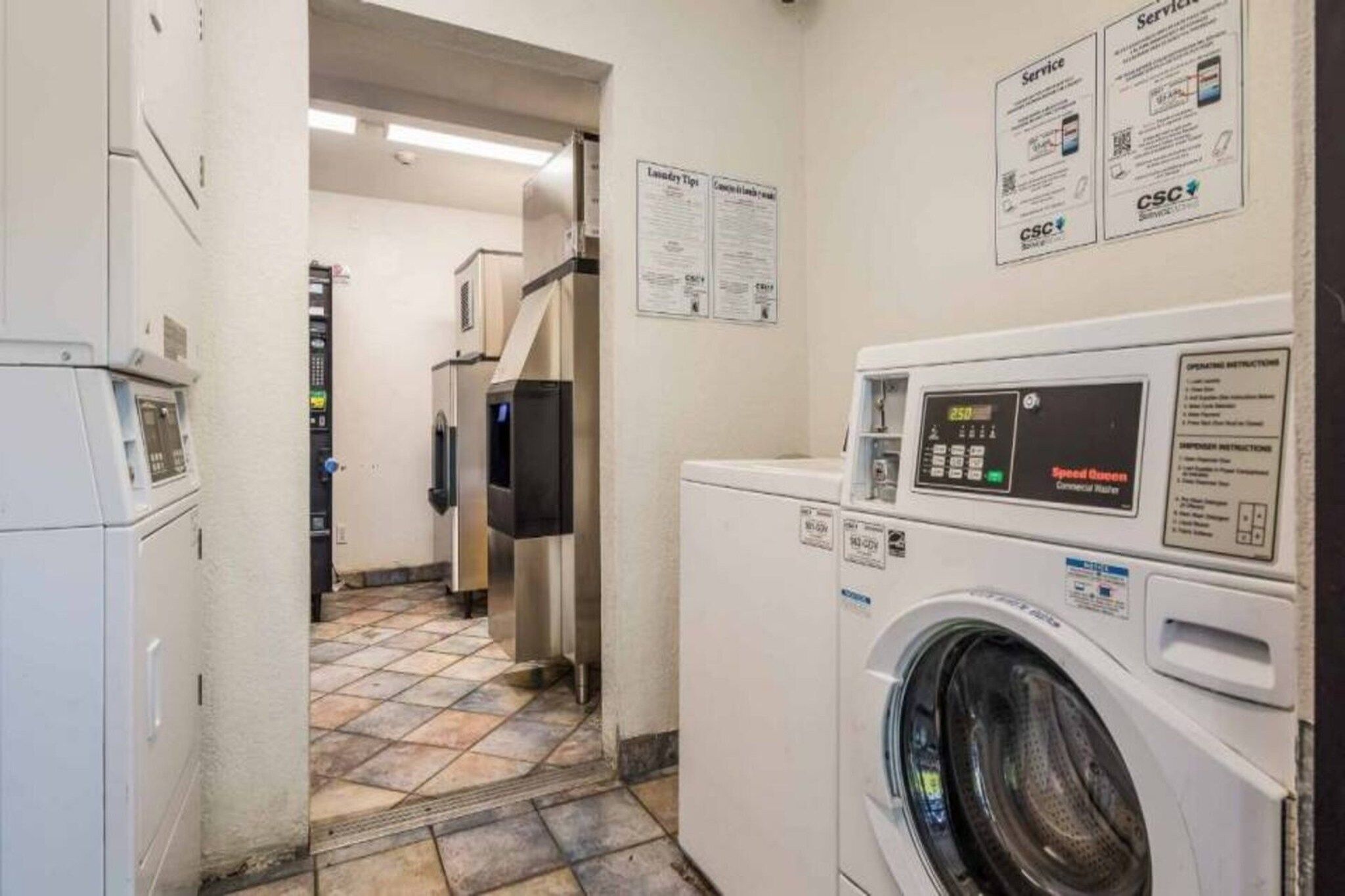 A laundry room with a front-loading washing machine, a dryer, and a wall-mounted control panel.