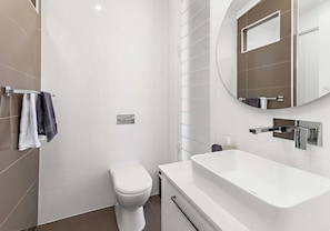 Ein modernes Badezimmer mit Toilette, Badewanne und großem Spiegel.