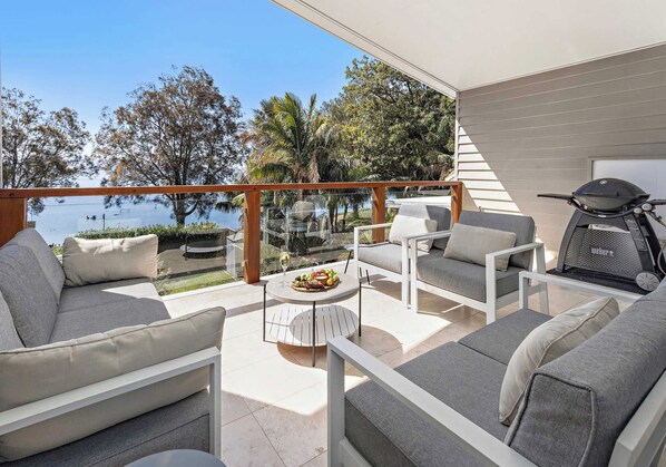Eine Terrassengruppe im Freien mit einem runden Tisch, zwei Sofas und einem Grill.
