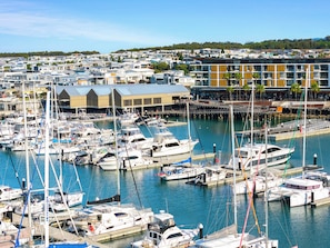 A marina with numerous boats docked, a waterfront restaurant, and residential buildings in the background.
