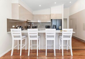 A modern kitchen with a central island, white cabinetry, and a wooden floor.