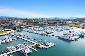 A marina with multiple docks and boats, surrounded by residential buildings and hills in the background. - Esplanade Lake House, Pet Friendly (Oak Flats)