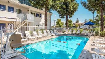 A swimming pool with lounge chairs and a building with blue doors in the background.
