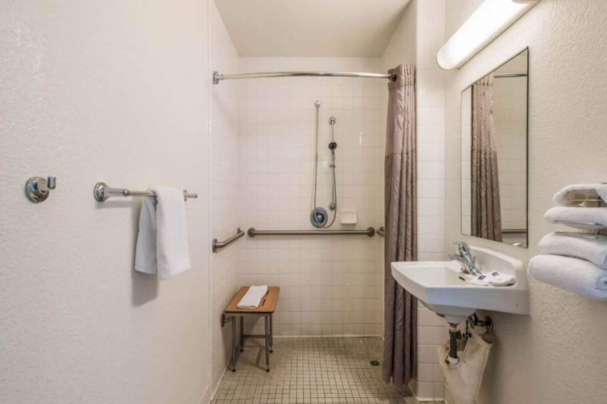 A small, compact bathroom with a shower, a sink, and a mirror.