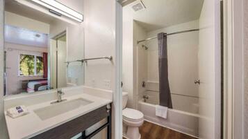 A bathroom with a large mirror, a sink, a toilet, and a shower area.