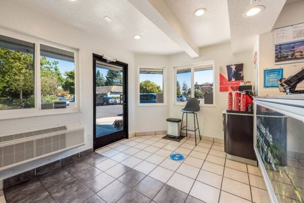 Un espace intérieur propre et bien éclairé, comprenant un comptoir d’accueil, une poubelle et une chaise.