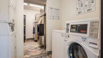 A laundry room with a front-loading washing machine, a dryer, and a wall-mounted control panel.
