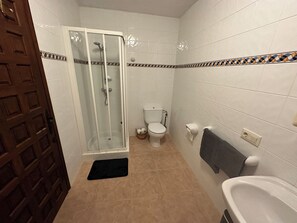 Ein Badezimmer mit einer Duschkabine, einer Toilette, einem Waschbecken und einem Handtuchhalter.