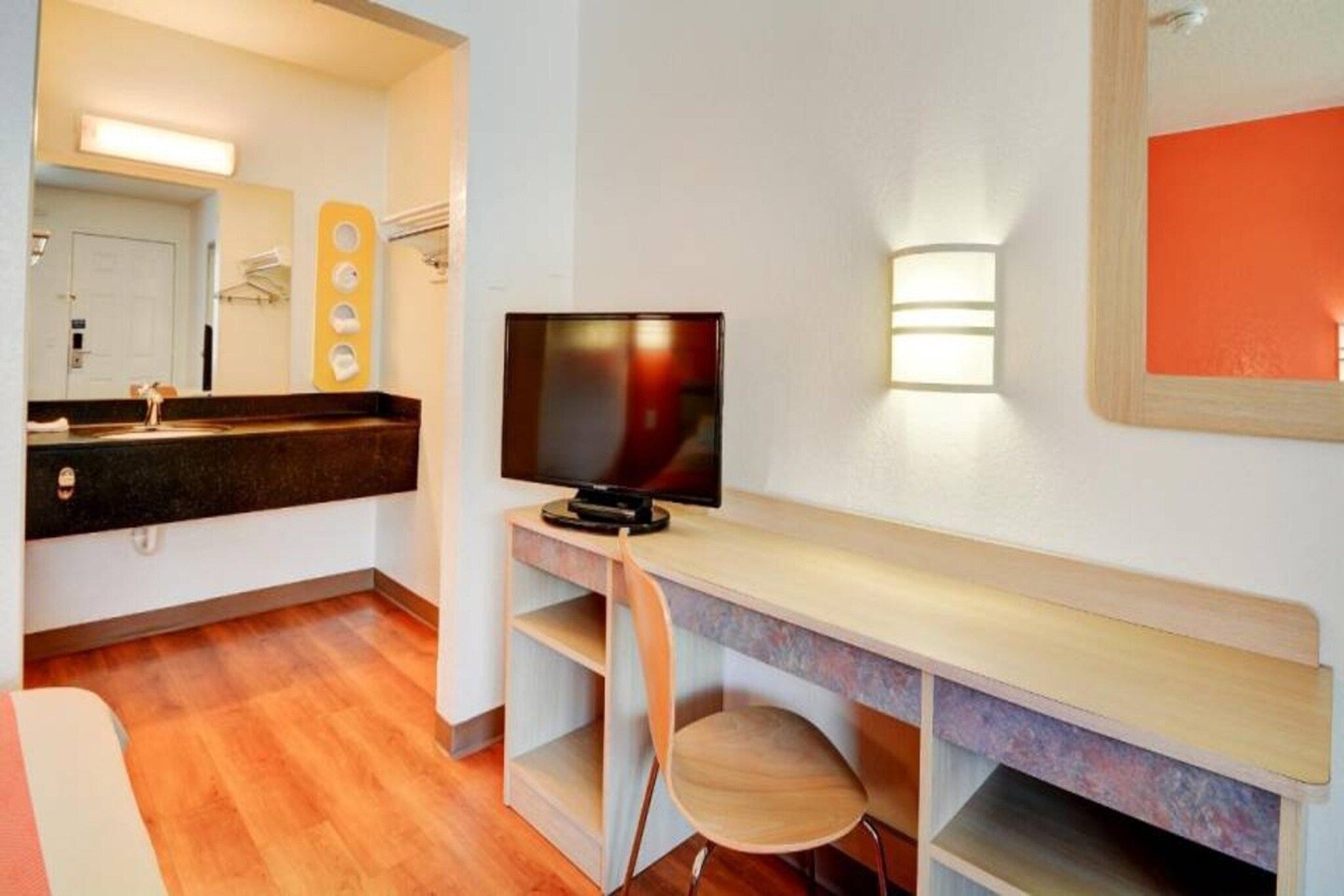 Una habitación de hotel compacta con escritorio de madera, televisor y una pequeña zona de estar.