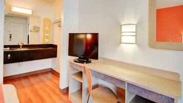 Una habitación de hotel compacta con escritorio de madera, televisor y una pequeña zona de estar.