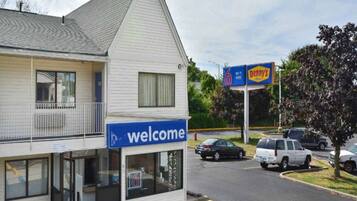A two-story building with a 'Welcome' sign, a parking lot, and a 'Penny's' sign in the background.