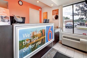 Un comptoir d’accueil d’un motel, avec une grande enseigne publicitaire indiquant les services proposés par l’établissement.