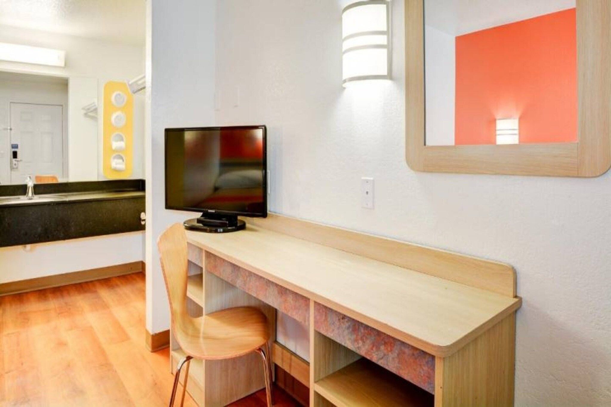 Um quarto com uma escrivaninha de madeira, uma televisão e duas cadeiras.