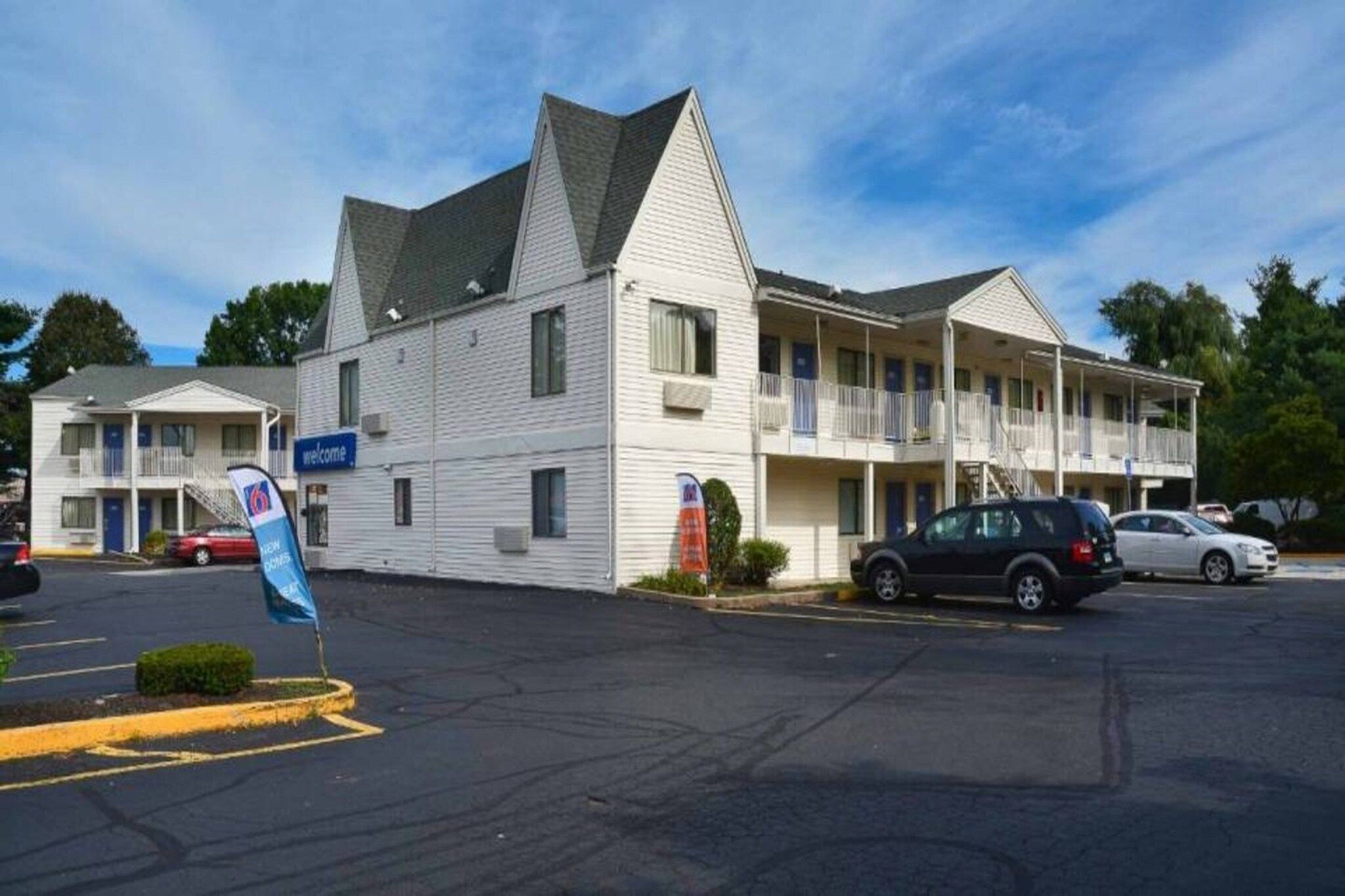 A motel with a two-story structure, a parking lot, and a flag indicating a nearby attraction.