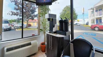 Ein Zimmer mit großem Fenster, Fernseher, Verkaufsautomaten und einem Sessel.
