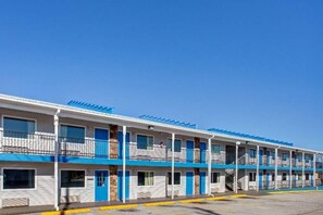 A motel with multiple rooms, each with a balcony and a window.