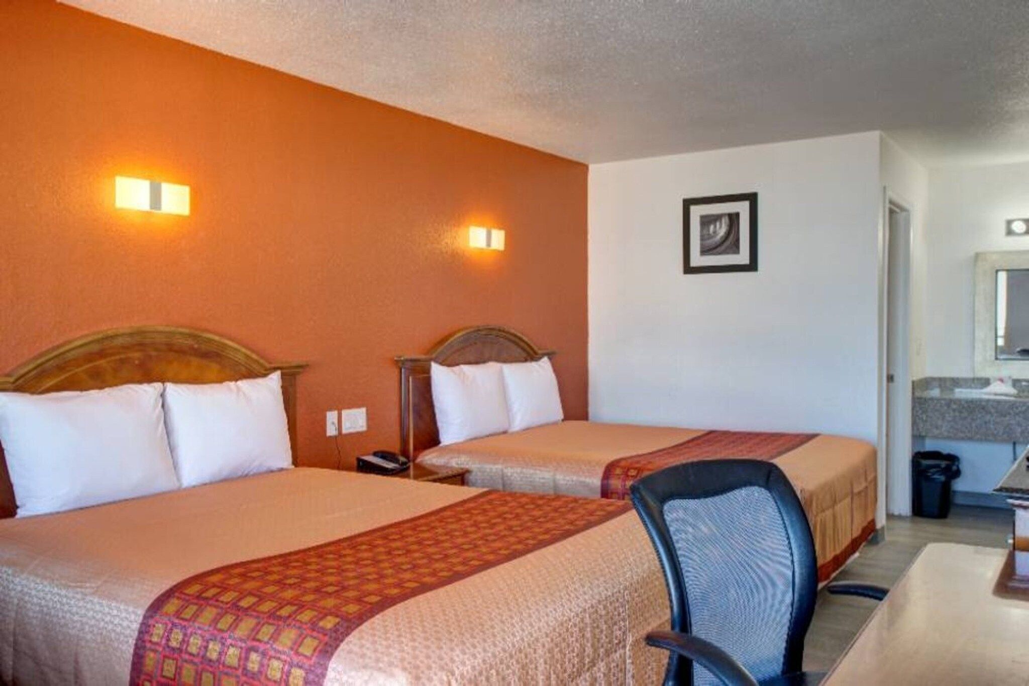 Ein Hotelzimmer mit zwei Betten, einem Schreibtisch und einem Stuhl.