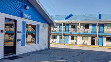 A motel with a blue and white exterior, a covered parking area, and a two-story building with multiple rooms.