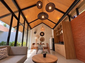 A modern kitchen with wooden cabinets, a dining area with a round table and chairs, and a ceiling with exposed beams and pendant lights. - Villa Sora by Kelle, Ubud (Gianyar)