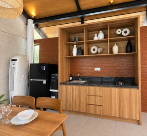 A modern kitchen with wooden cabinetry, a black countertop, and a built-in sink. - Villa Sora by Kelle, Ubud (Gianyar)