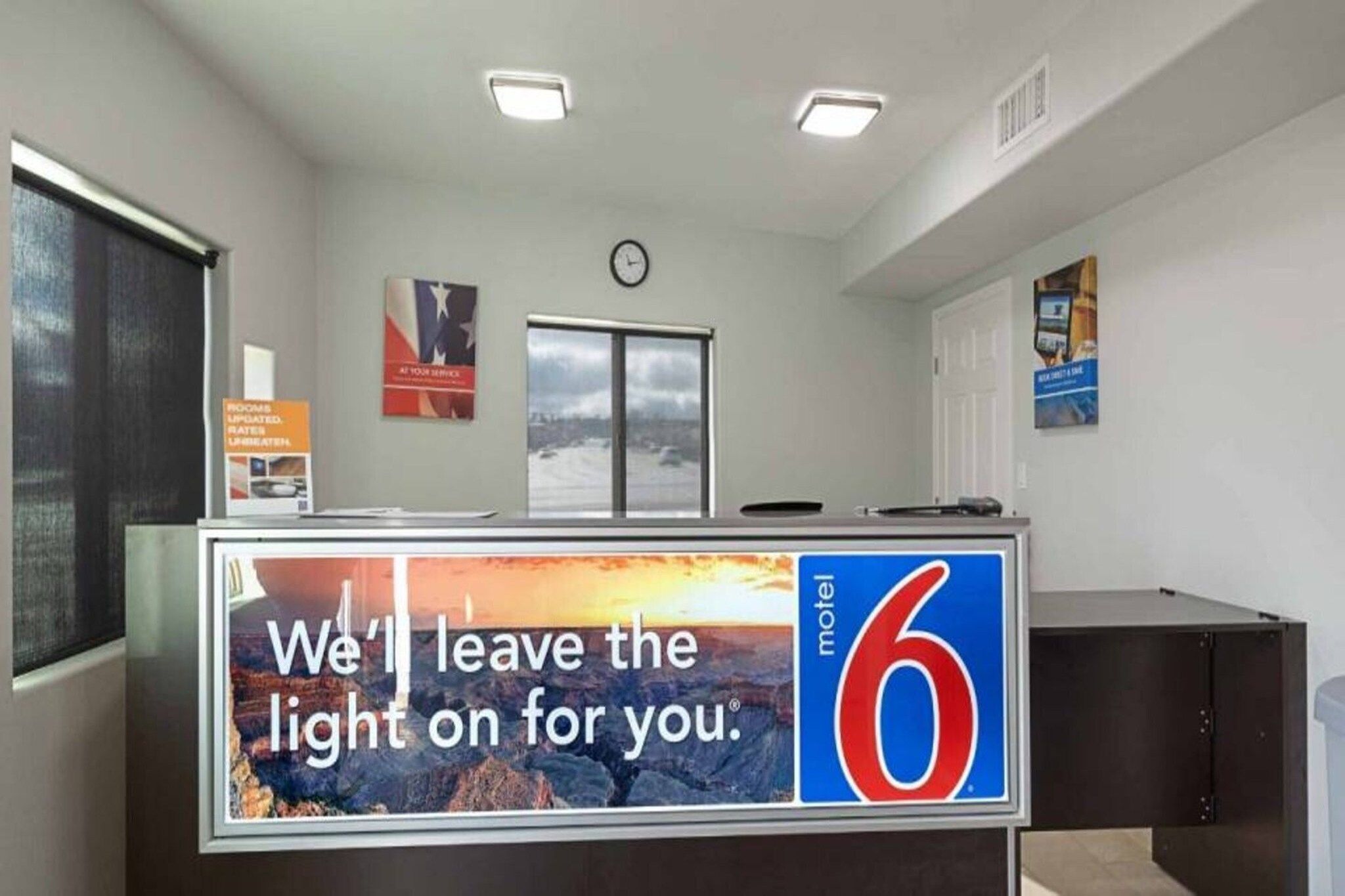 A motel reception desk with a large sign reading 'We'll leave the light on for you.'