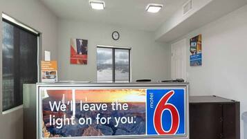 A motel reception desk with a large sign reading 'We'll leave the light on for you.'