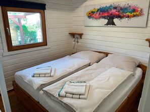 A room with two beds, a window, a painting of a tree, and wooden walls. - fewo1846 - Utkiek / Three-bedroom vacation home with private beach access (Glücksburg (Ostsee))
