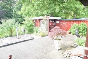 Ein Garten mit Kiesweg, einem roten Gebäude und einem Vogelfutterhaus.