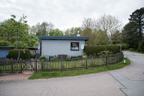 Ein kleines, eingeschossiges Haus mit Backsteinfassade, einer Satellitenschüssel und einem Holzzaun.