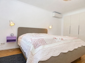 Ein Schlafzimmer mit einem Bett, Nachttischlampen, einem Nachttisch, einer Klimaanlage und einem Kleiderschrank.