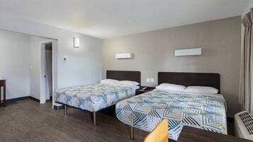 A hotel room with two beds, a desk, and a chair.