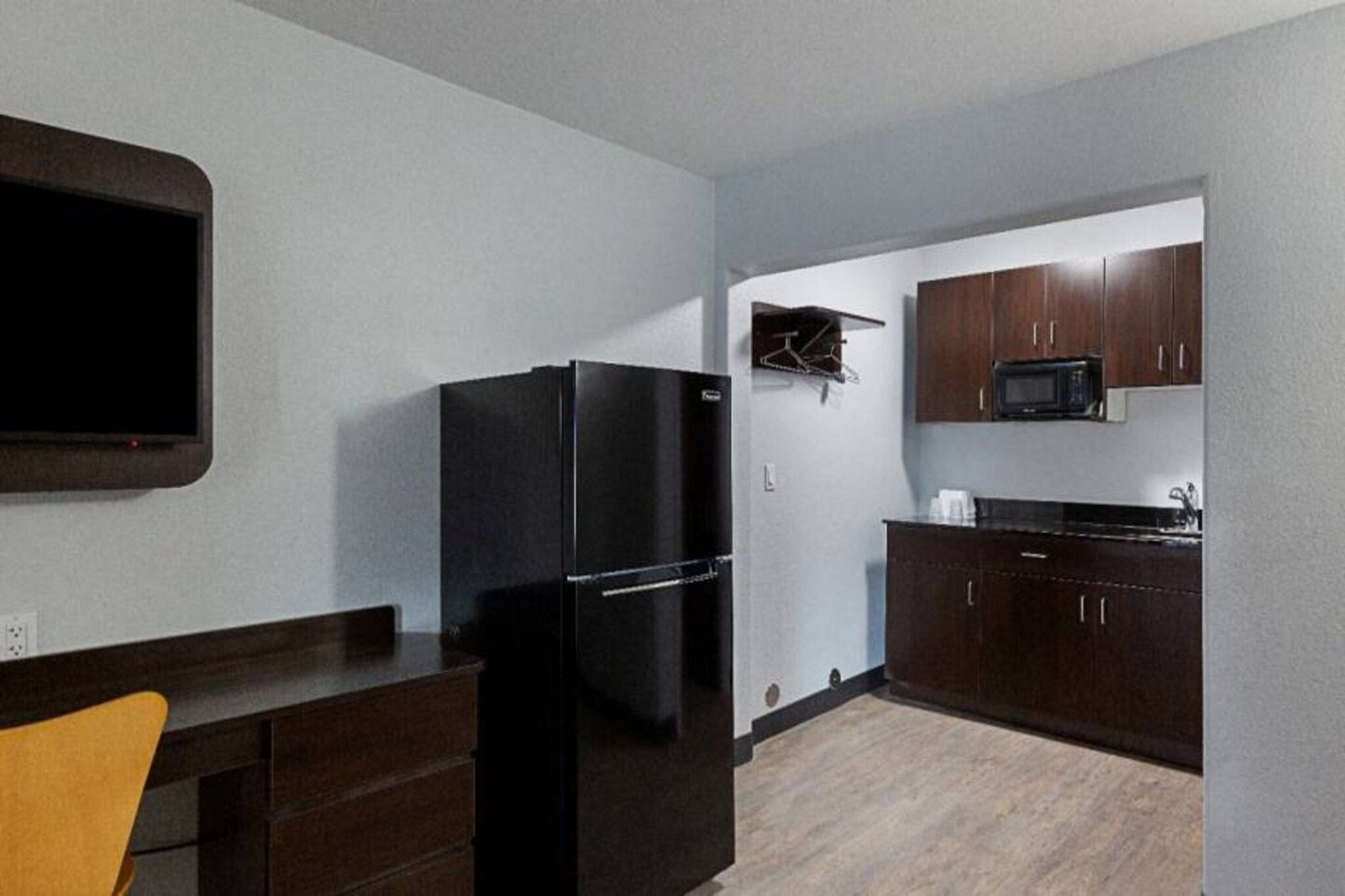 A compact kitchen with a refrigerator, microwave, and wooden cabinets.