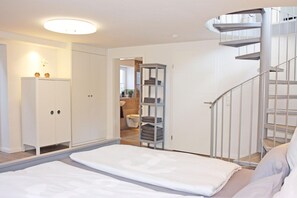 A bedroom with a bed, a wardrobe, a bathroom, and a staircase. - fewo1846 - StrandNest - House with a view of the fjord, a fireplace, a sauna, and 3 bedrooms - (Glücksburg (Ostsee))