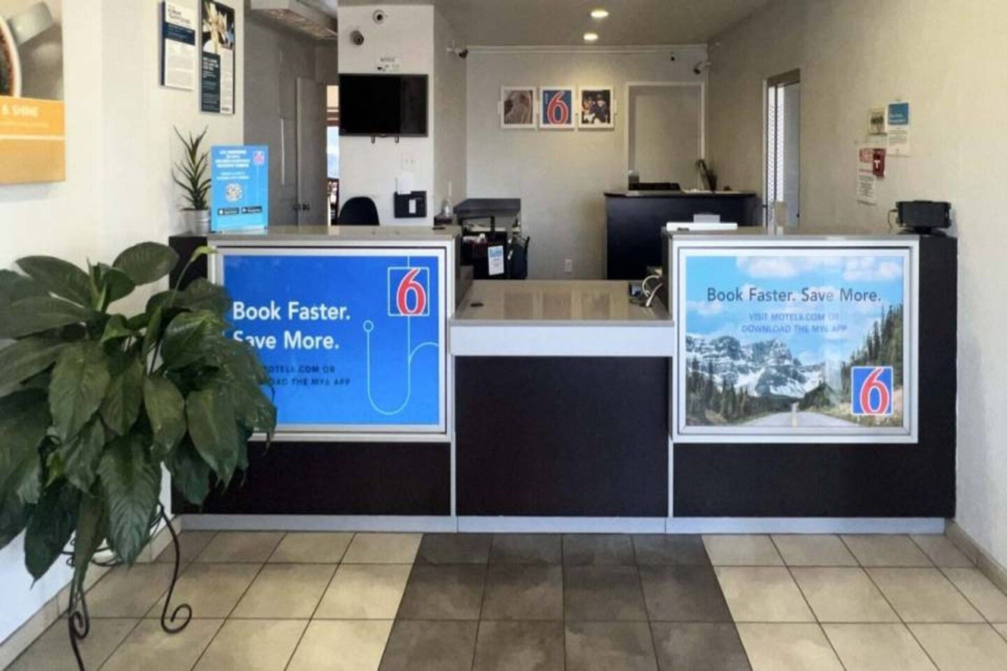 A reception area with a counter, a plant, and two informational posters.