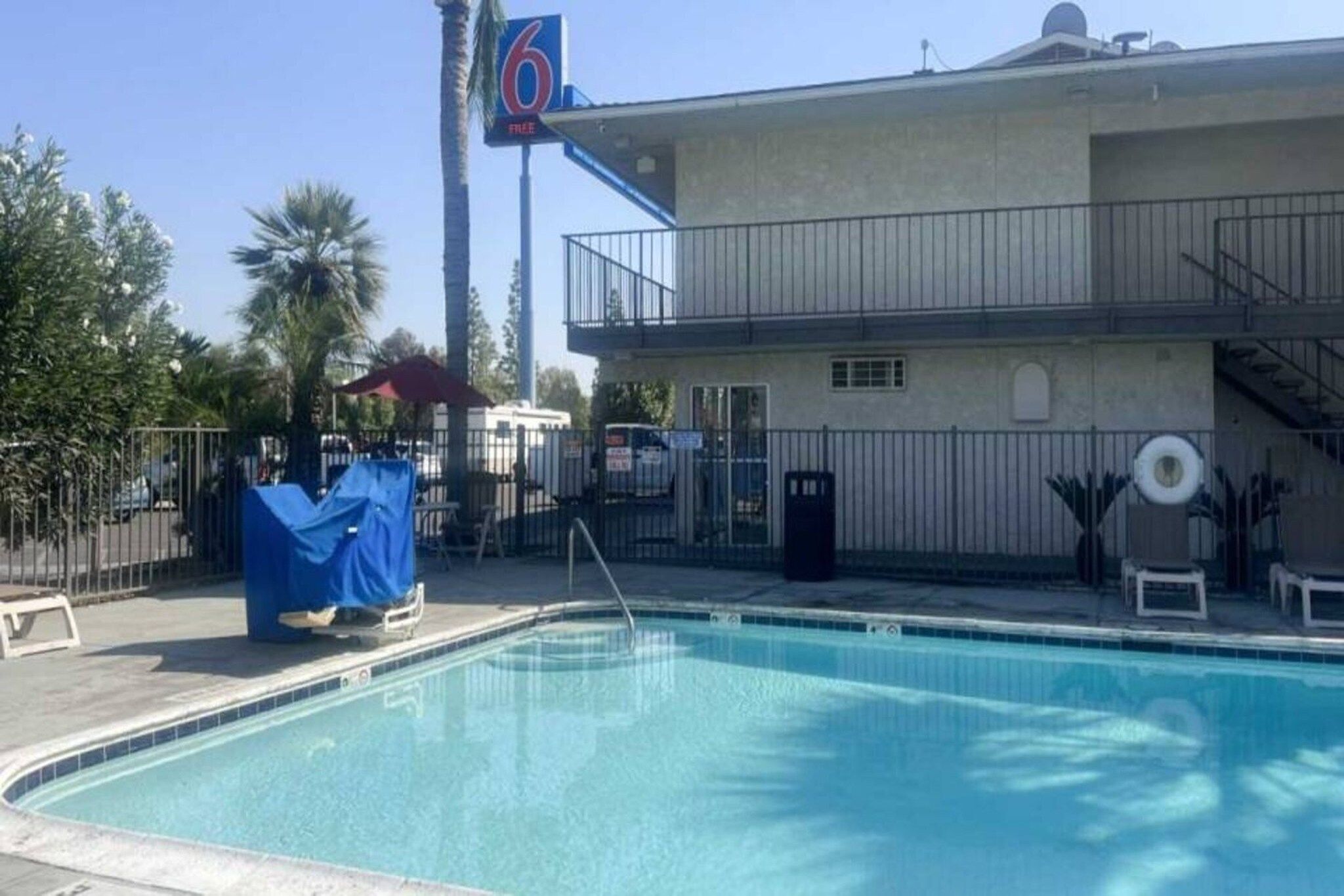 Ein Schwimmbecken mit überdachtem Bereich, ein Gebäude mit Balkon und ein Schild mit der Nummer 6.