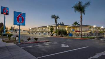 A hotel with a clear road in front, a sign indicating the entrance, and a well-lit building with multiple floors.